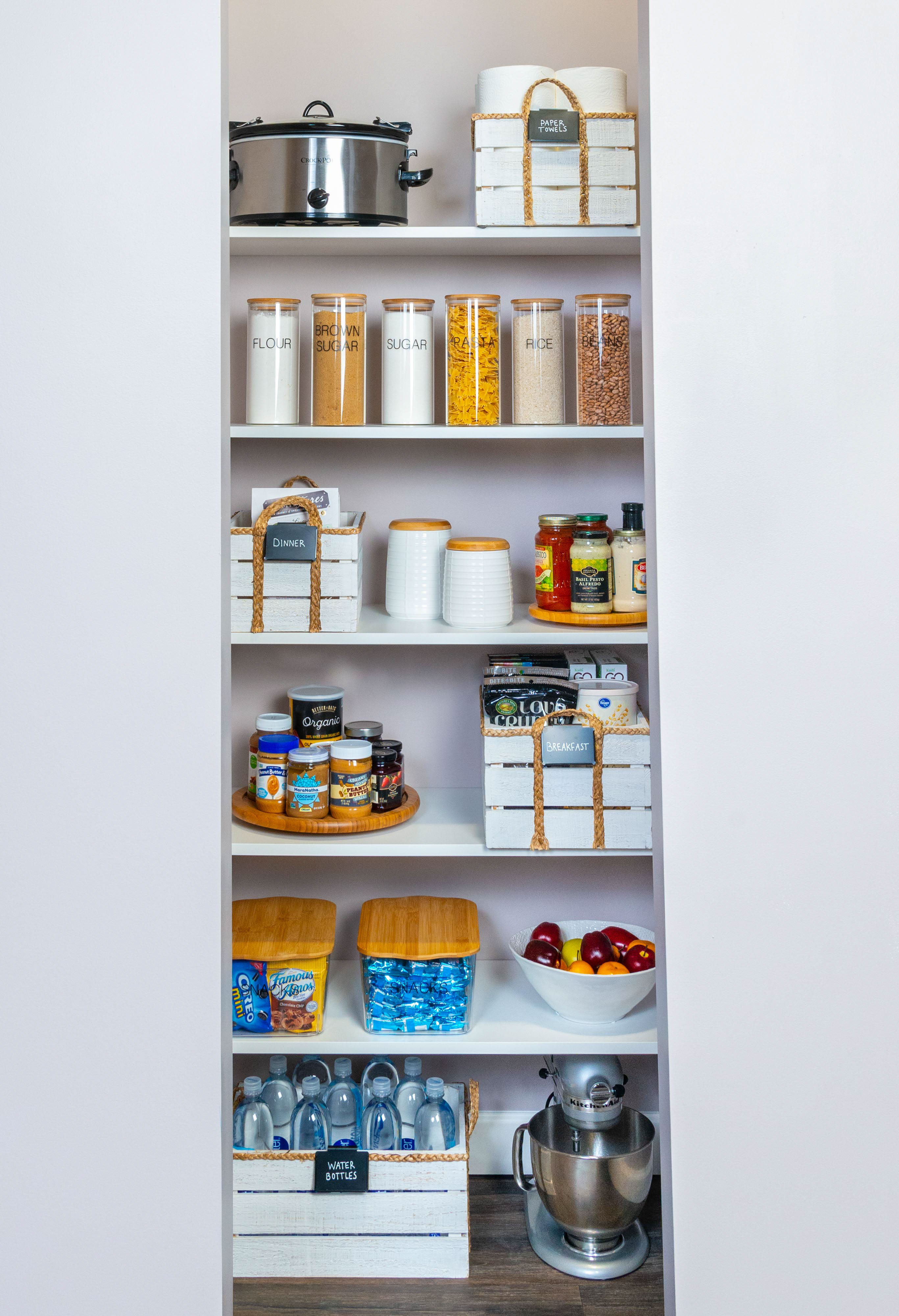 VUE Reach-In Pantry in White with baskets, food, water bottles with neutral wall.