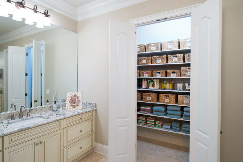 White freedomRail linen storage closet with baskets, towels and other personal care items.