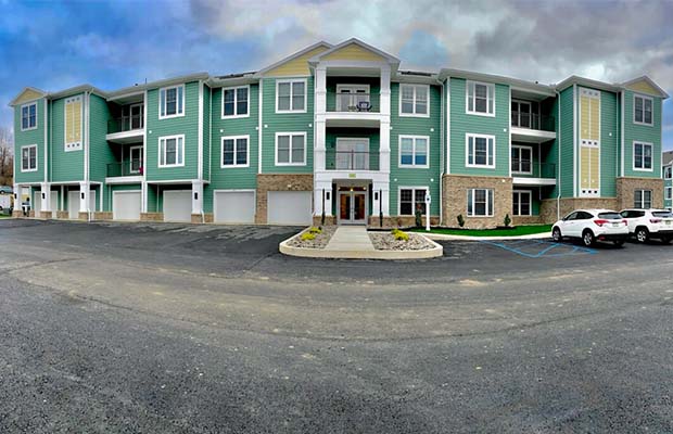 Three-story green apartment complex, Magnolia Court Apartments.