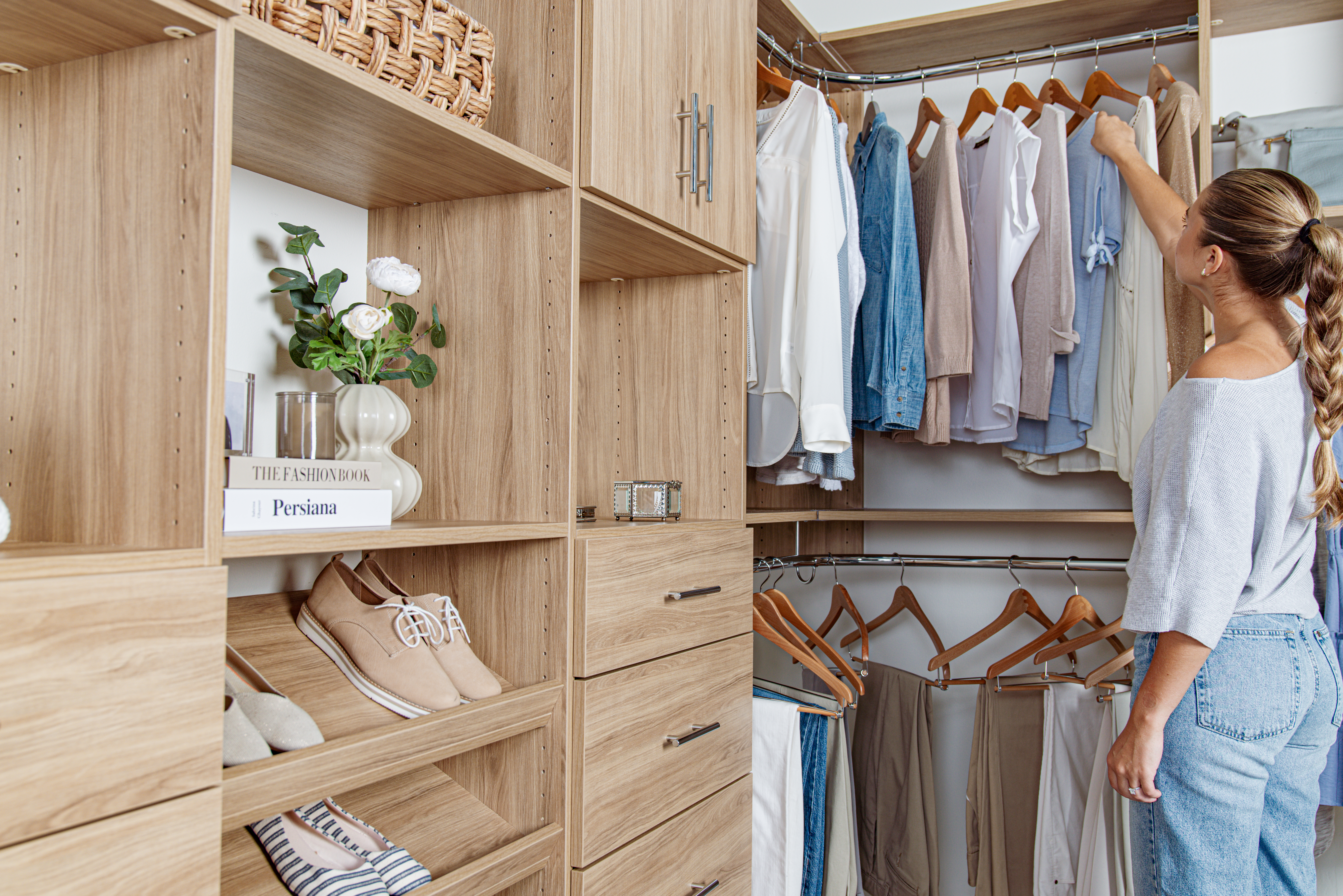 Select product line walk-in closet in Blonde Oak finish with women clothing and accessories, 2 decorative books that have text that say